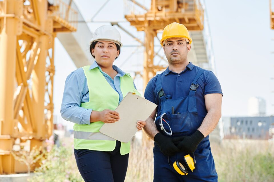Two engineers in hard hats and safety vests on site